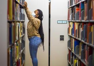 student in library stacks